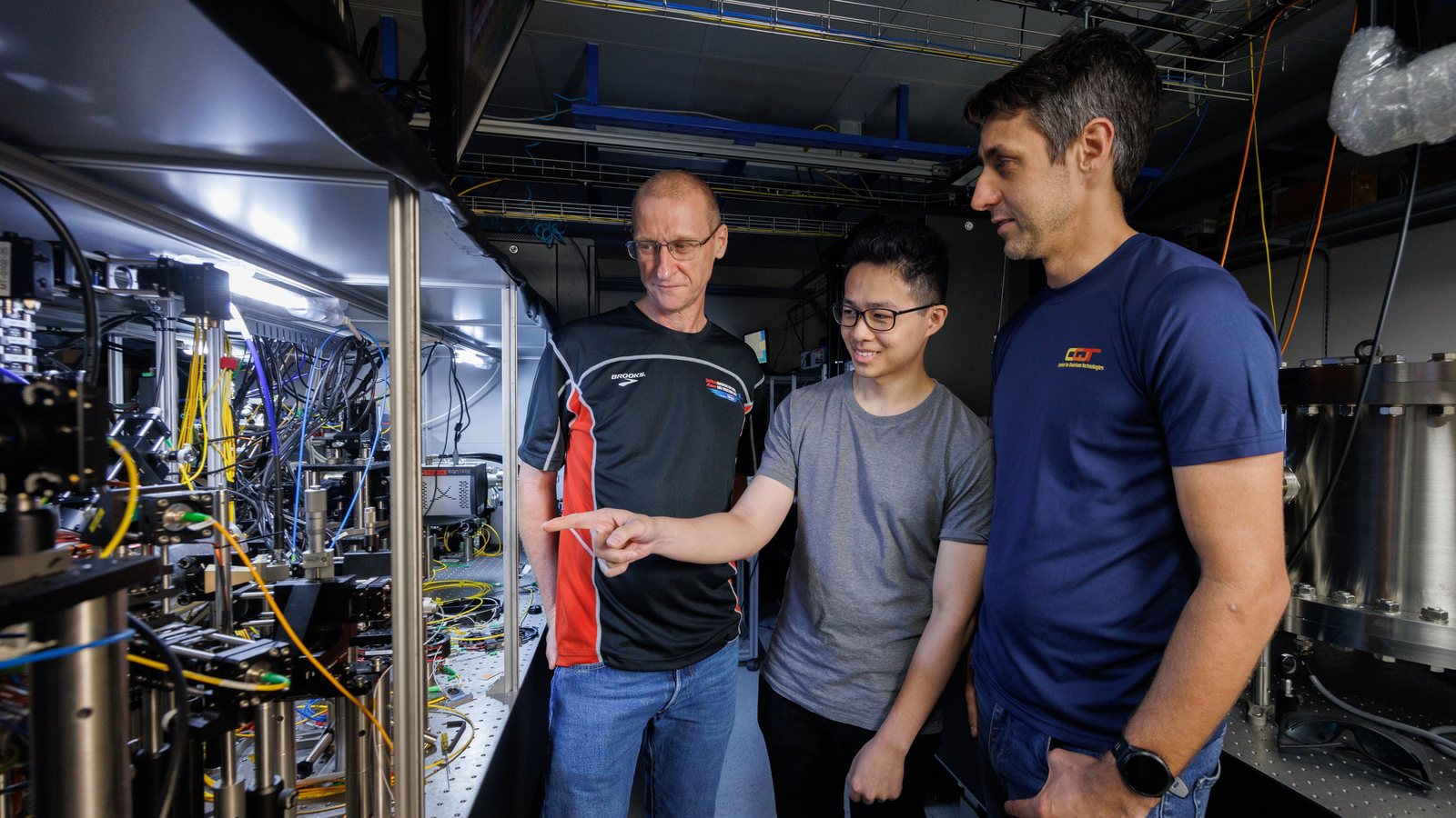 Associate Professor Murray Barrett, PhD student Michael Lee and Senior Research Scientist Kyle Arnold inspecting optical equipment in the lutetium atomic clock laboratory at the Centre for Quantum Technologies